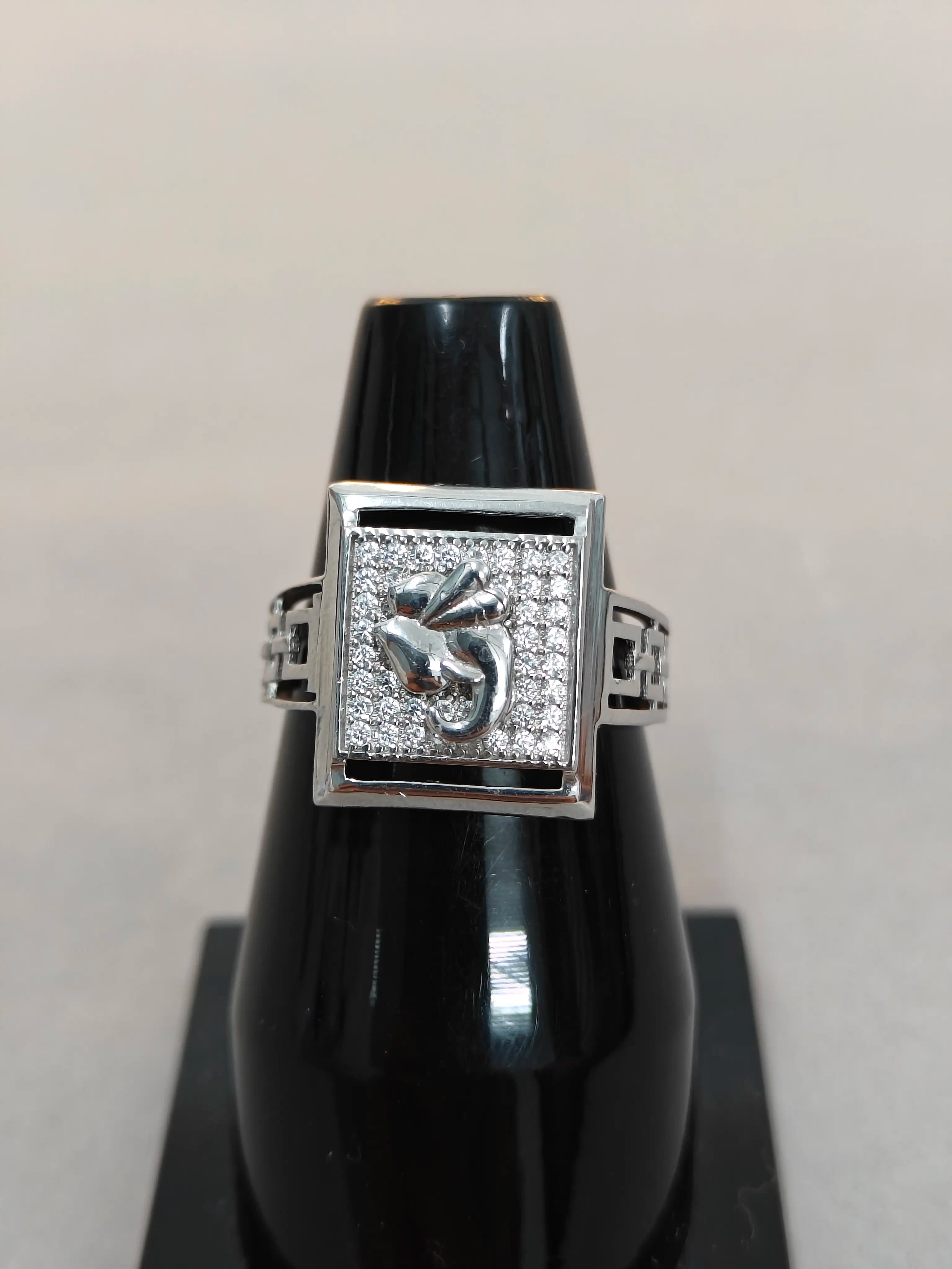 Silver ring with gemstones on a black stand against a light gray background
